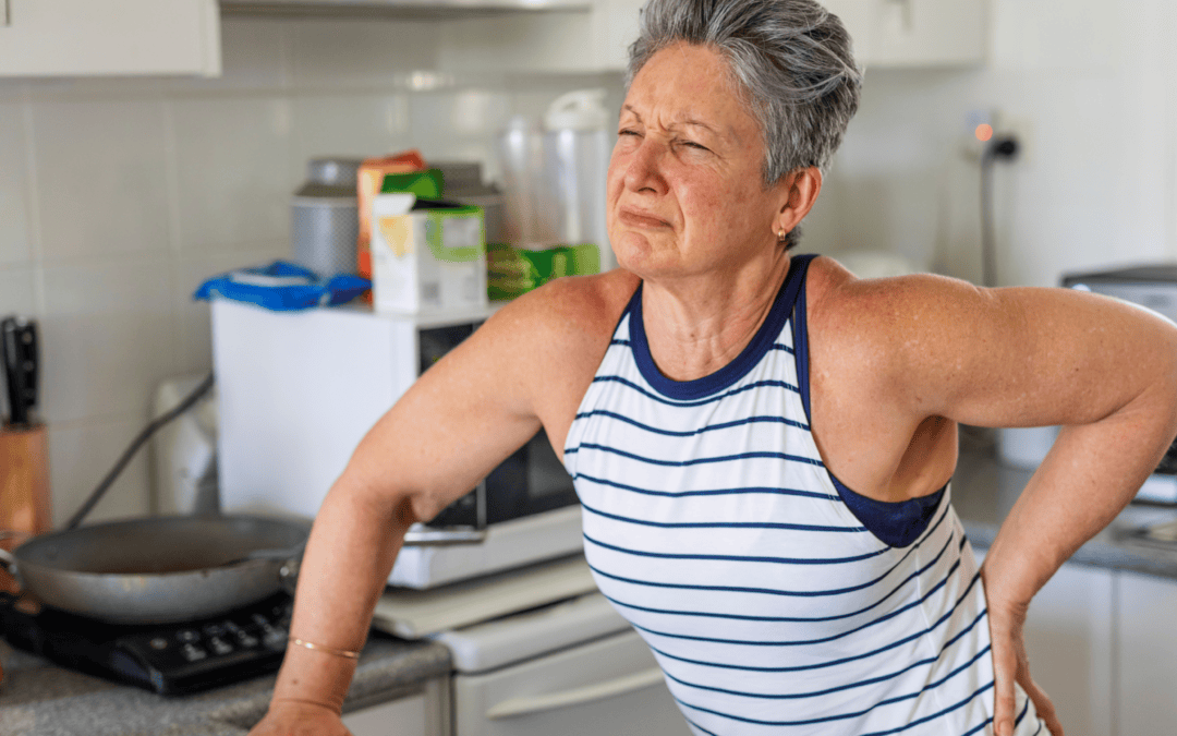 Elderly woman experiencing back pain in kitchen, seeking relief and improved well-being.