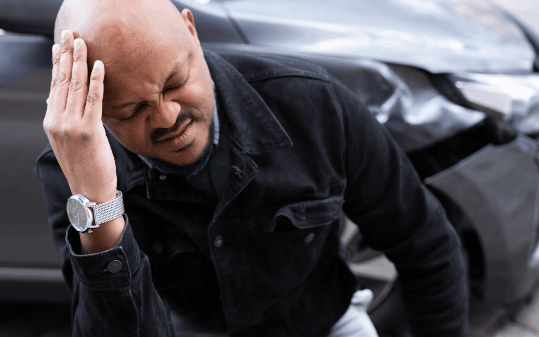 Man holding head in pain after a car accident, seeking relief from injury.
