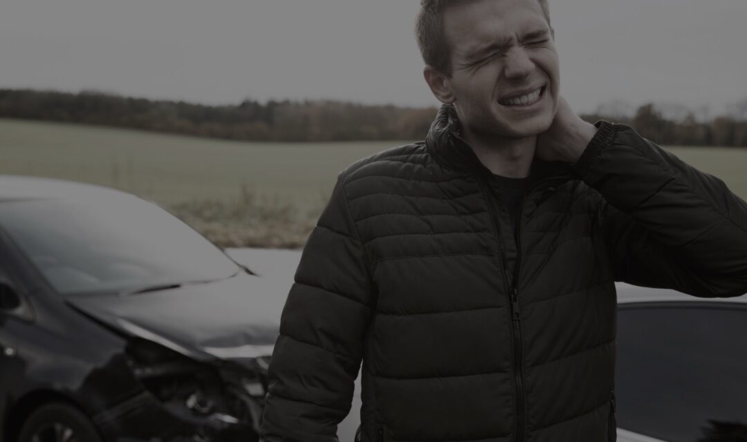 Man experiencing neck pain holding neck, outdoor setting, seeking relief.