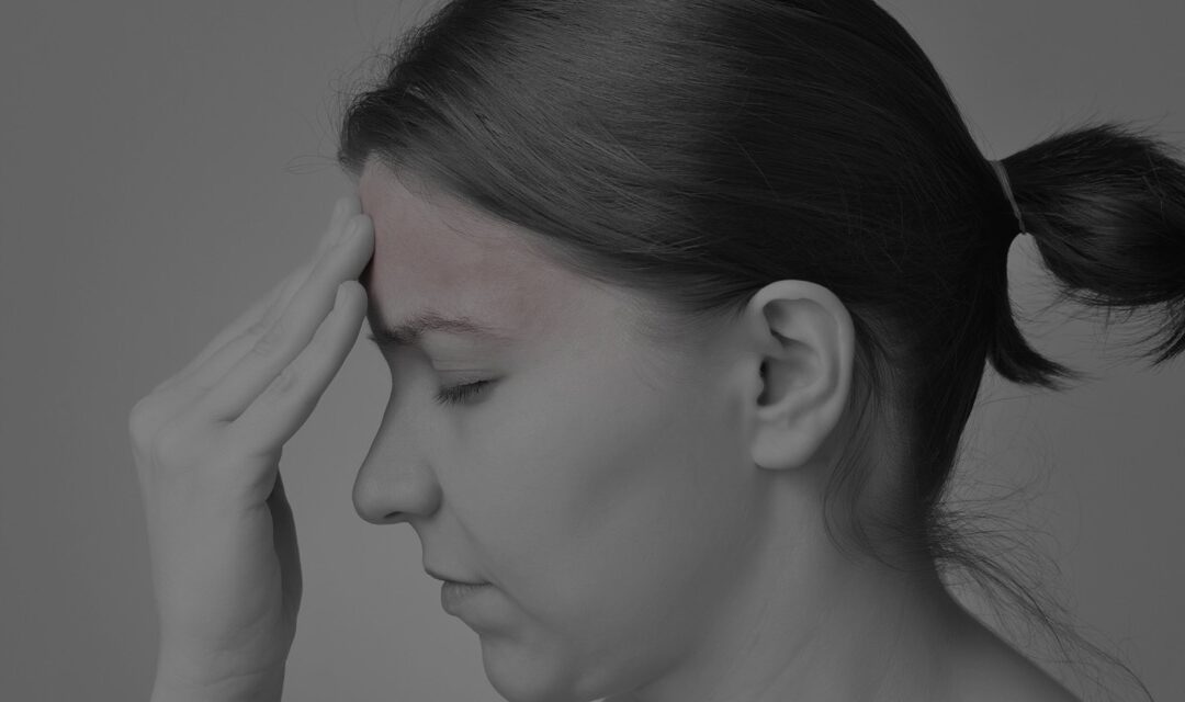 Woman experiencing headache, seeking pain relief at NW Pain Center.