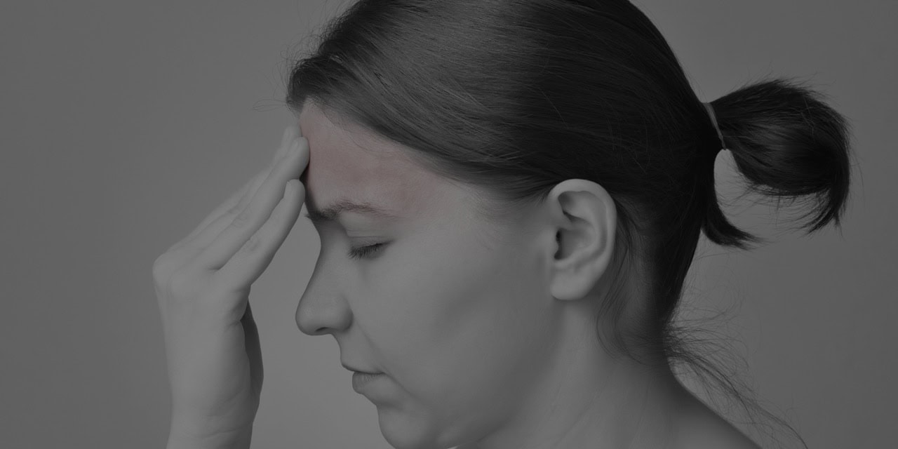 Woman experiencing headache, seeking pain relief at NW Pain Center.