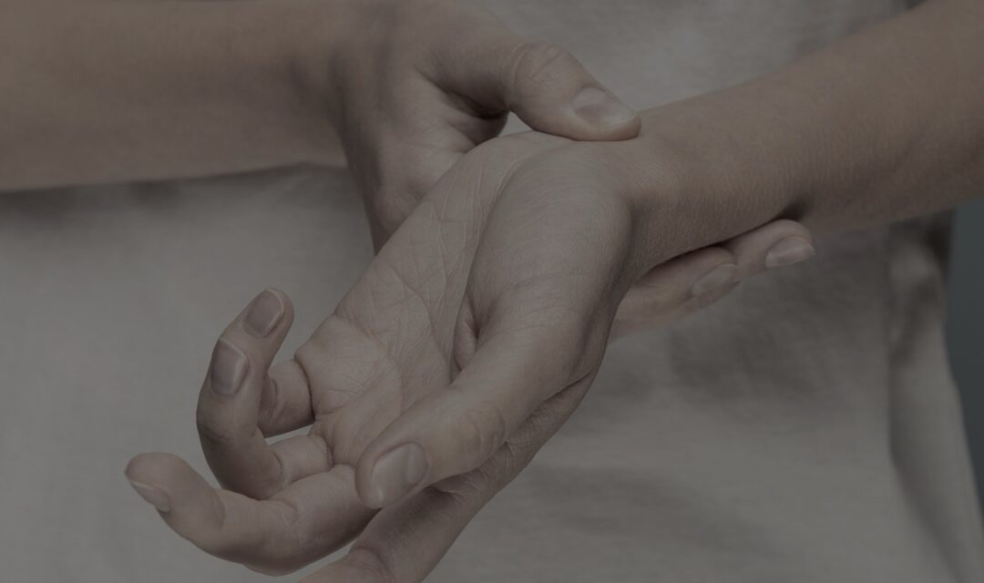 Healthcare professional examining a patient's hand for pain assessment.
