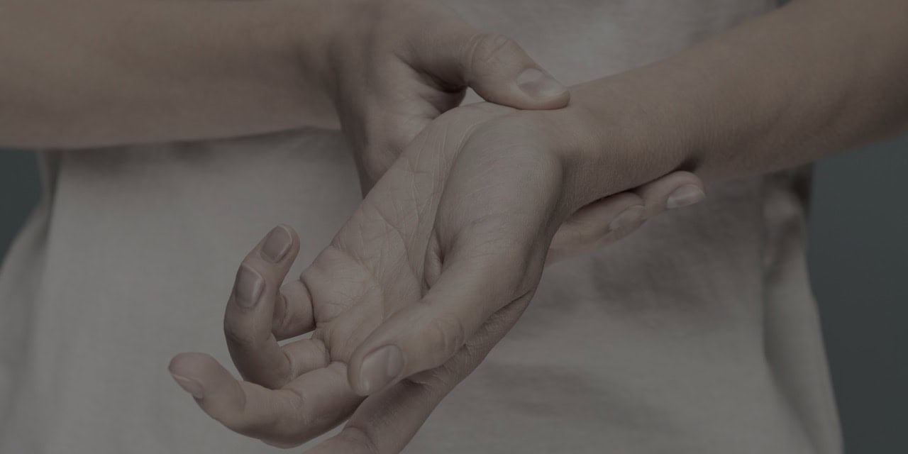 Healthcare professional examining a patient's hand for pain assessment.