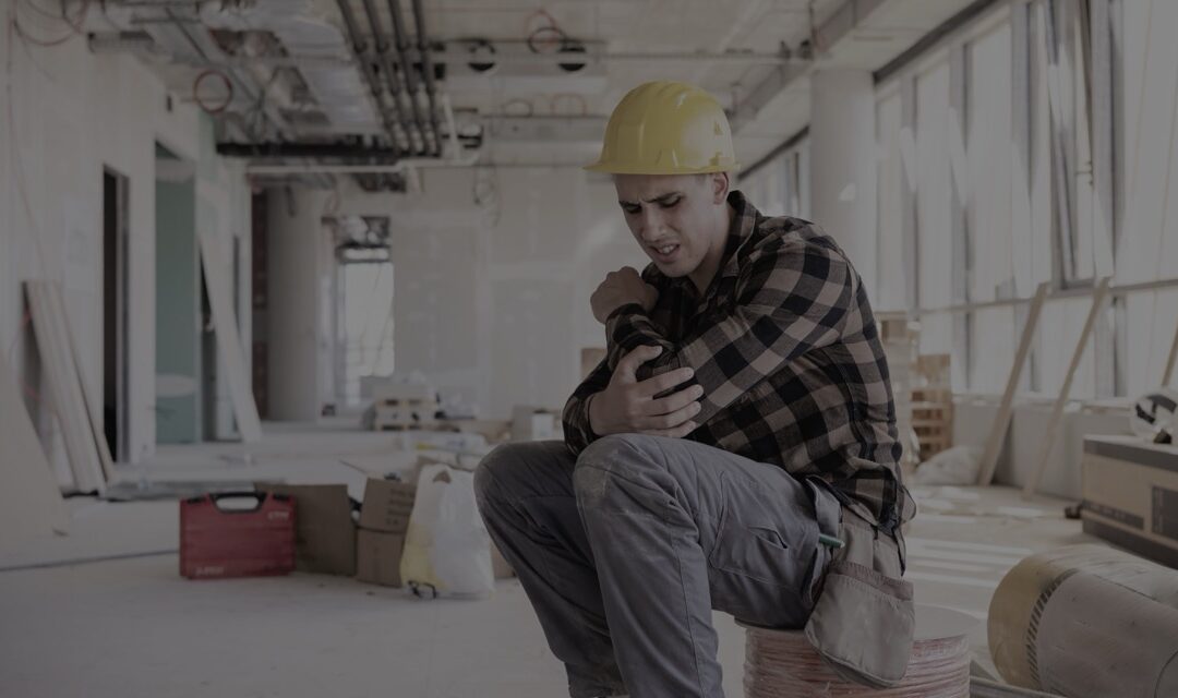 Construction worker examining a knee brace in a healthcare facility.