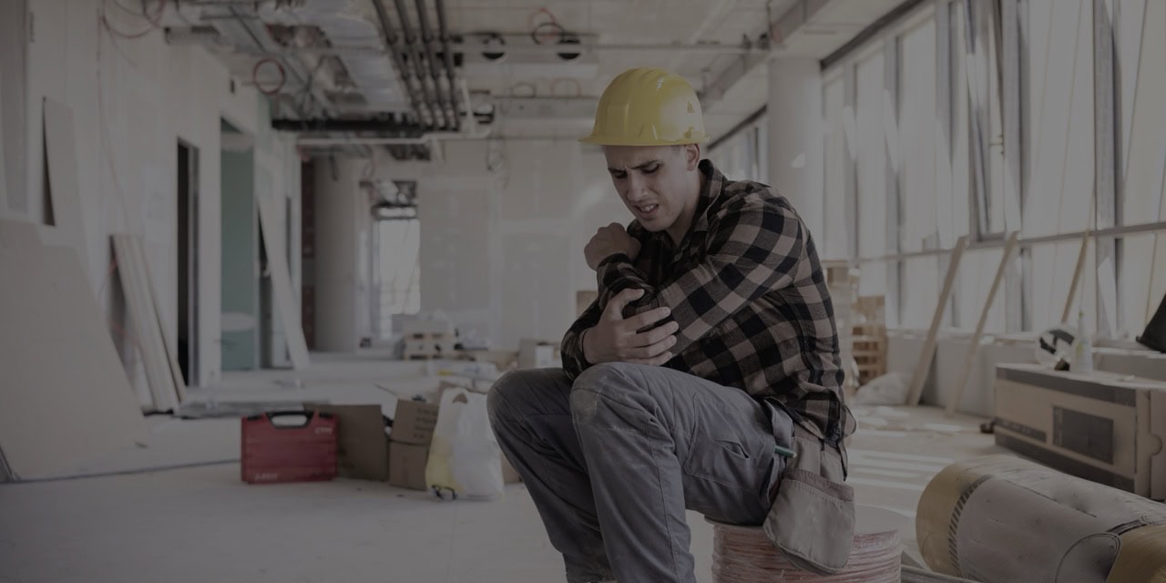 Construction worker examining a knee brace in a healthcare facility.